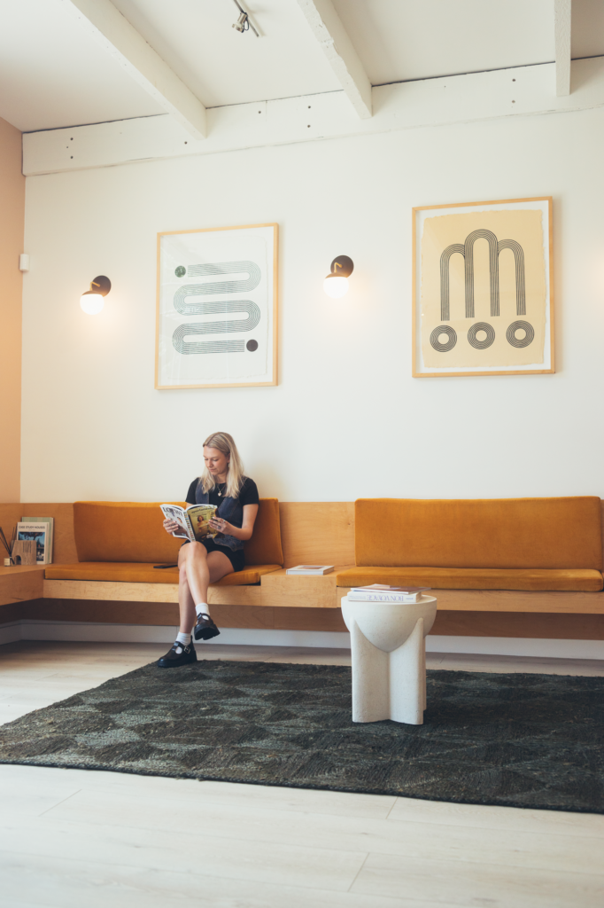 Patient reading a magazine in a modern dental office waiting room with warm seating, minimalist artwork, and a calm, welcoming atmosphere.