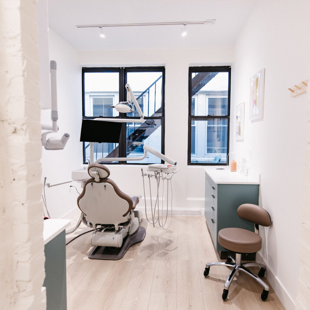 Bright modern dental treatment room with advanced dental chair, overhead light, monitor, and clean, minimalist clinic design.