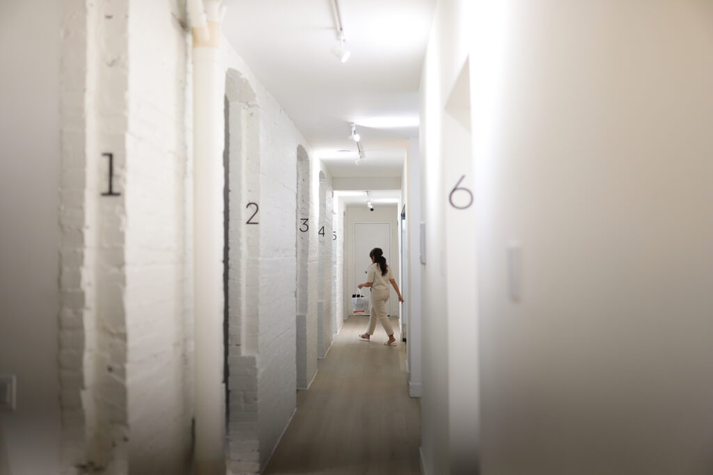 Dental professional walking through a contemporary dental clinic hallway with private treatment rooms