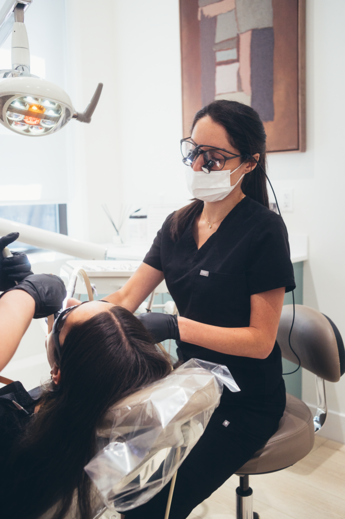 Dentist performing treatment at SMILELOUNGE in Brooklyn, NY with patient reclining